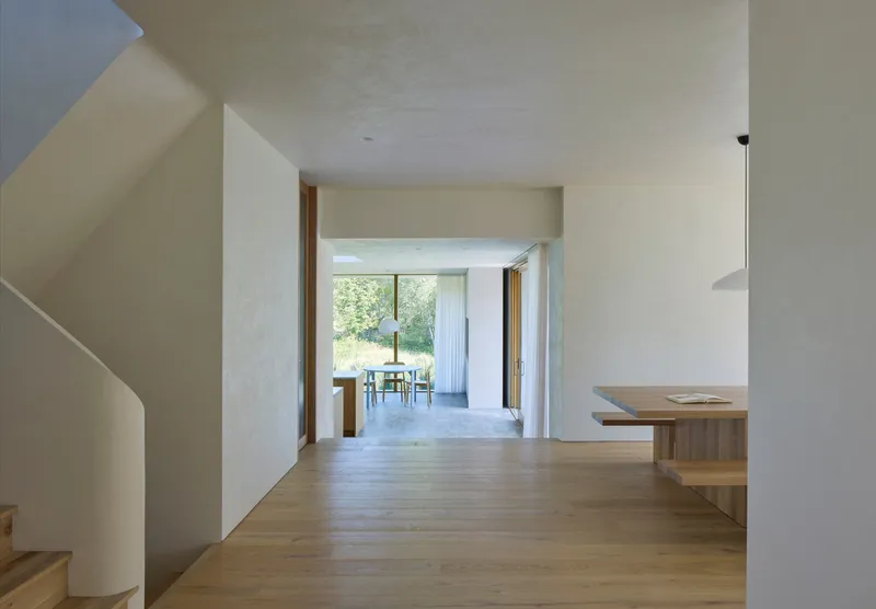 Interior hallway with oak flooring leading through white plastered walls to garden view beyond