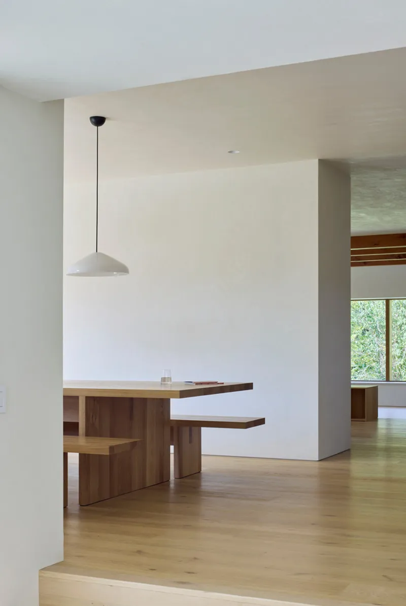 Timber desk nook with integrated seating and pendant lamp beside a white plaster wall