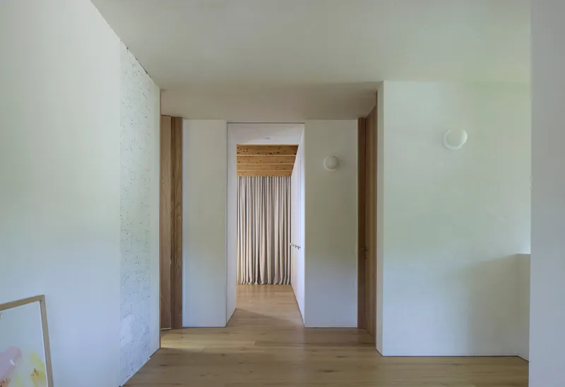 Interior hallway with oak flooring and timber-framed doorways leading to corridor with exposed timber ceiling