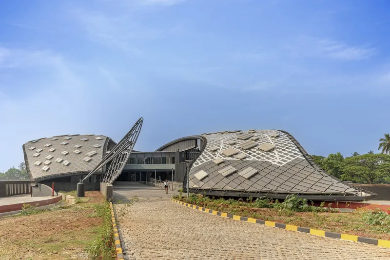 Approach view of the sculptural wing-like roof volumes rising above a paved entry plaza