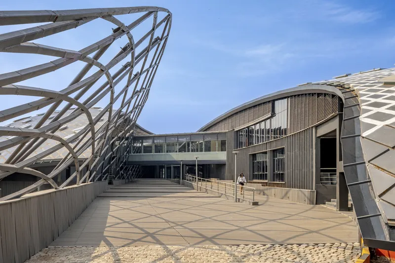 Roof terrace with exposed steel lattice structure framing views toward glazed facade and central courtyard
