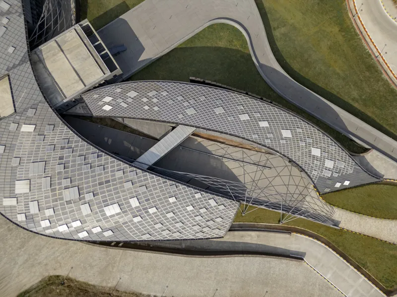 Aerial view of the undulating roof with mosaic tile paving and triangular skylights amid green lawns