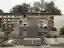 This image depicts a cemetery with a large brick mausoleum wall featuring numerous arched niches. In