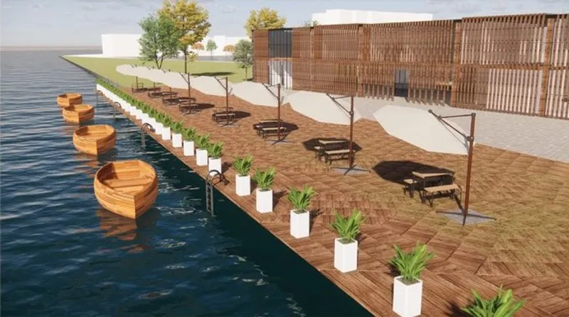 Waterfront seating area with shaded tables and boats.