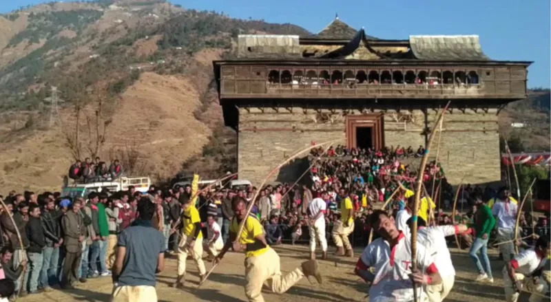 Stone and timber structure with elevated viewing gallery where festival crowds gather in afternoon light