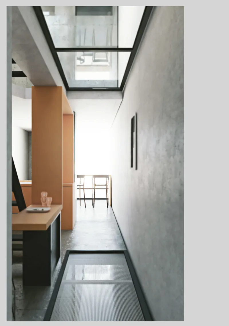 Glass floor panel set into concrete flooring beneath the angular skylight with white chair beyond