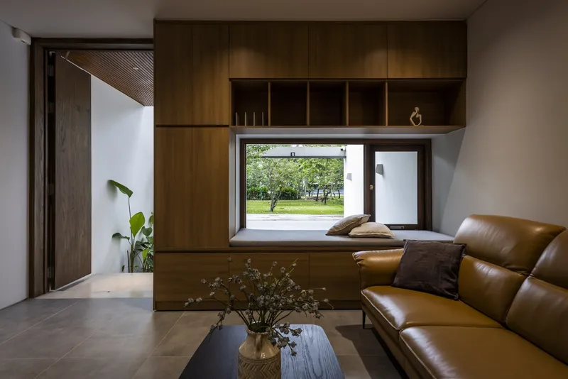 Built-in timber window seat with cushions framing a view of a lawn and trees outside