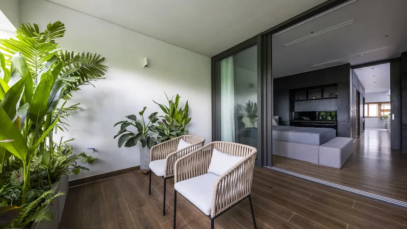 Timber deck terrace with woven chairs and tropical plants against a white courtyard wall