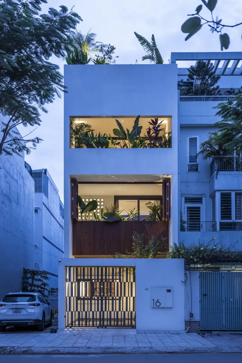 Street facade with stacked horizontal window openings and illuminated slatted gate at twilight