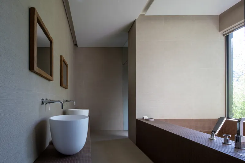 Bathroom with freestanding vessel sink, tile-clad tub surround and window overlooking greenery