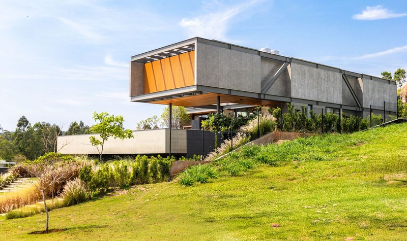 Side view of the cantilevered volumes on a sloping lawn with timber screens and concrete walls