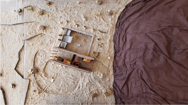 Aerial view of a scale model set in pale sand with a draped fabric landscape element