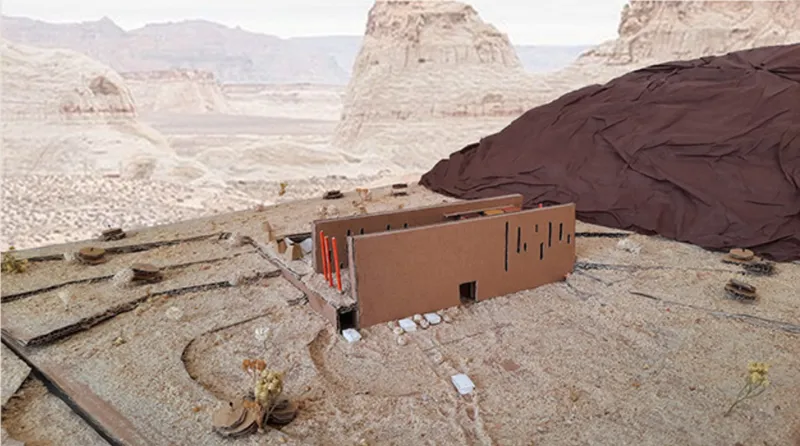 Physical model placed on rocky desert terrain with pale sandstone formations in the distance