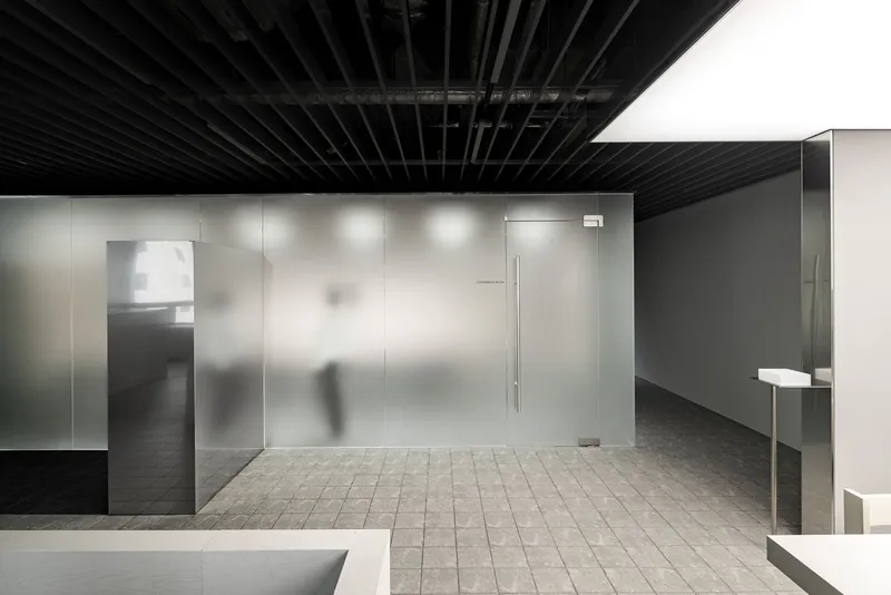 Frosted glass enclosure with sliding door and a person walking through the tiled corridor