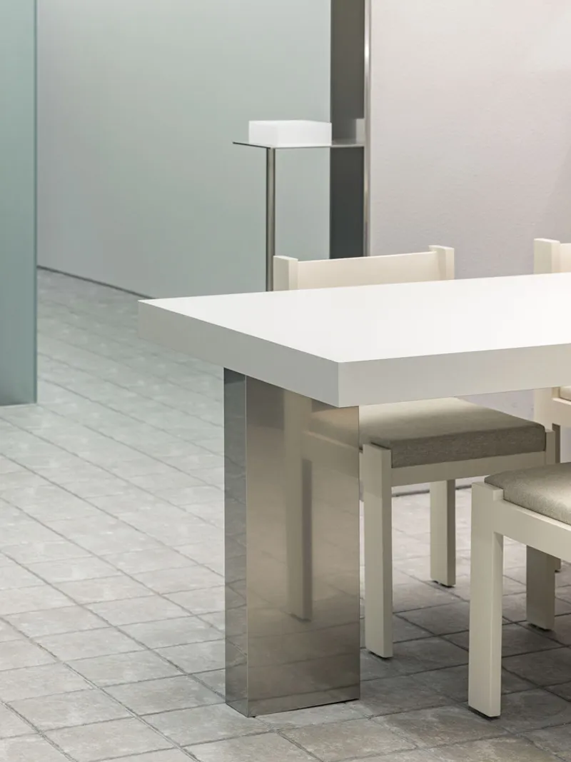 White table with steel base and upholstered chairs next to frosted glass partition