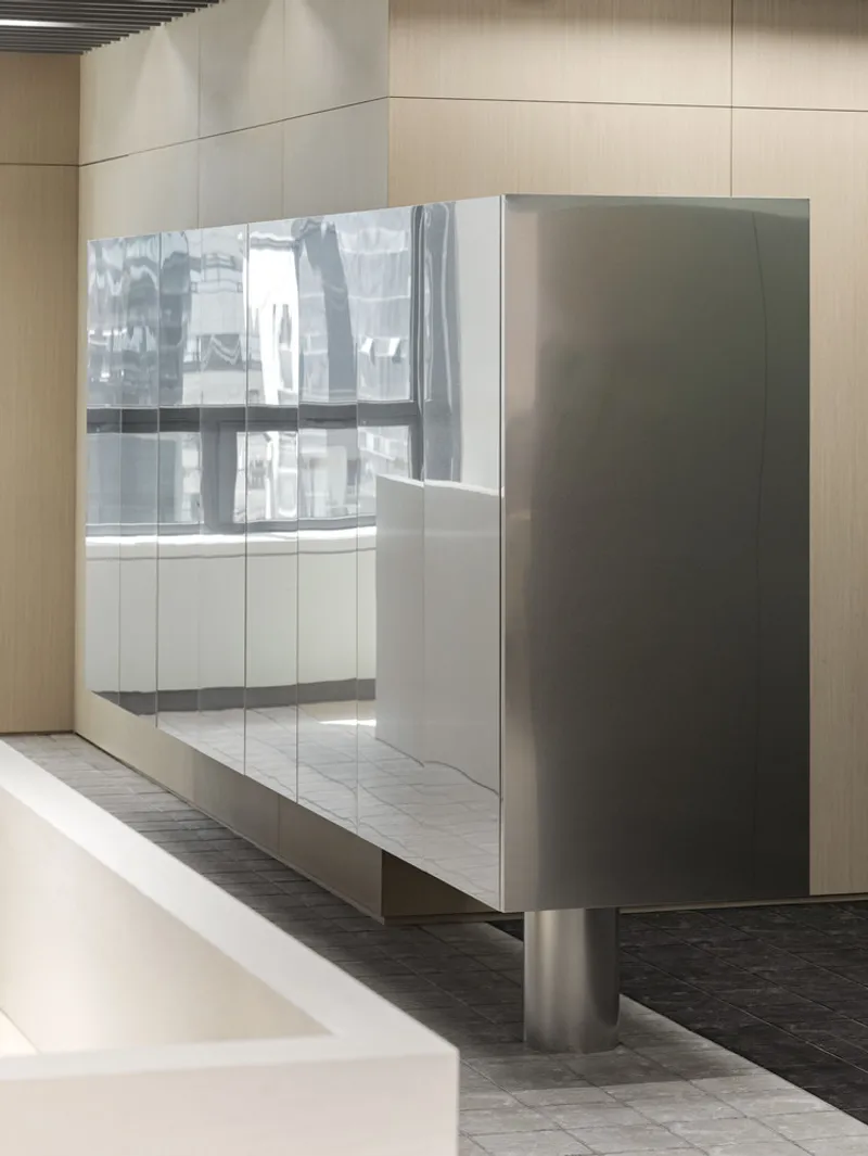 Freestanding storage unit with frosted glass doors on cylindrical steel legs over dark tile flooring
