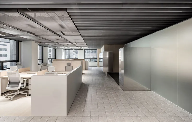 Long view through the office showing alternating zones of black baffle ceiling and grey acoustic panels