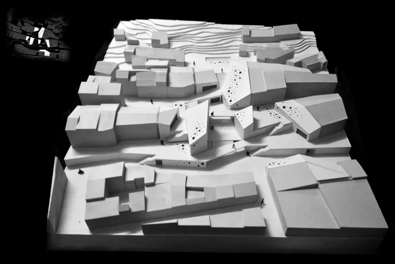 Physical model showing angular volumes clustered around a central courtyard amid surrounding urban fabric