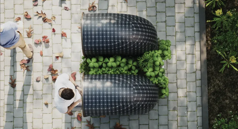 Aerial view of twin curved solar panel roofs flanking green vegetation on light paver surface with pedestrians