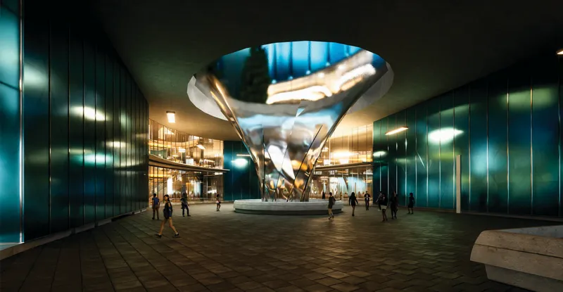 Ground-level plaza with reflective green metal facade and illuminated conical skylight at dusk