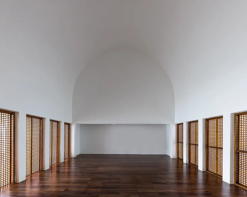 Barrel-vaulted interior with timber lattice doors lining the curved walls above dark wood flooring