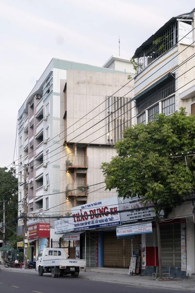 Street view of the concrete facade with diagonal ribbed panels beside a shopfront and power lines