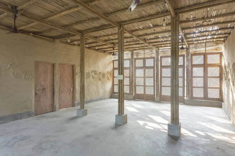 Interior room with bamboo slat ceiling, concrete floor and louvered timber shutters filtering afternoon light