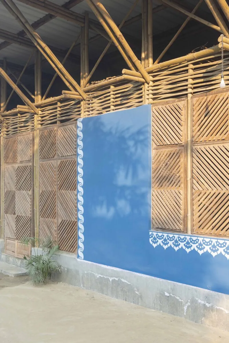 Exterior corner showing woven bamboo parapet above blue plaster wall with decorative white lace trim