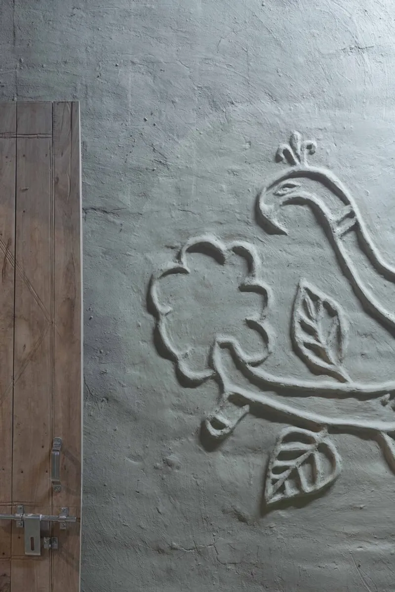 White plastered wall with relief carved floral motif beside a timber door with metal latch