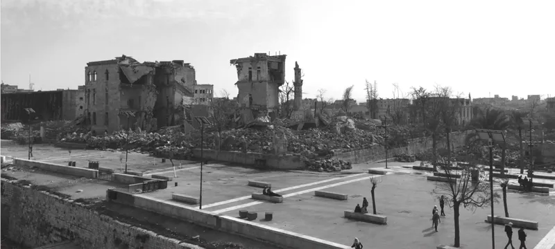 Public plaza with stone benches and paving beside rubble remains of damaged buildings