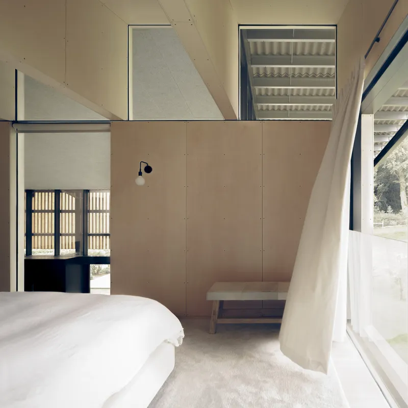 Bedroom with plywood paneling and a view through slatted screens to the landscape