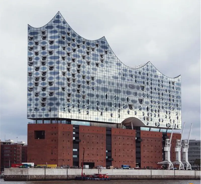 Waterfront facade with wave-shaped glass curtain wall rising above a red brick podium under overcast sky