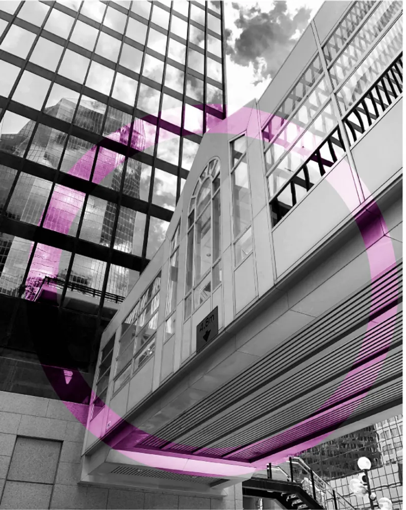 Upward view of glass curtain wall facade and elevated pedestrian bridge with colored overlay accents
