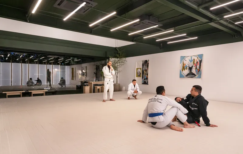 Training session on white mat flooring beneath green exposed ceiling with linear fluorescent lighting