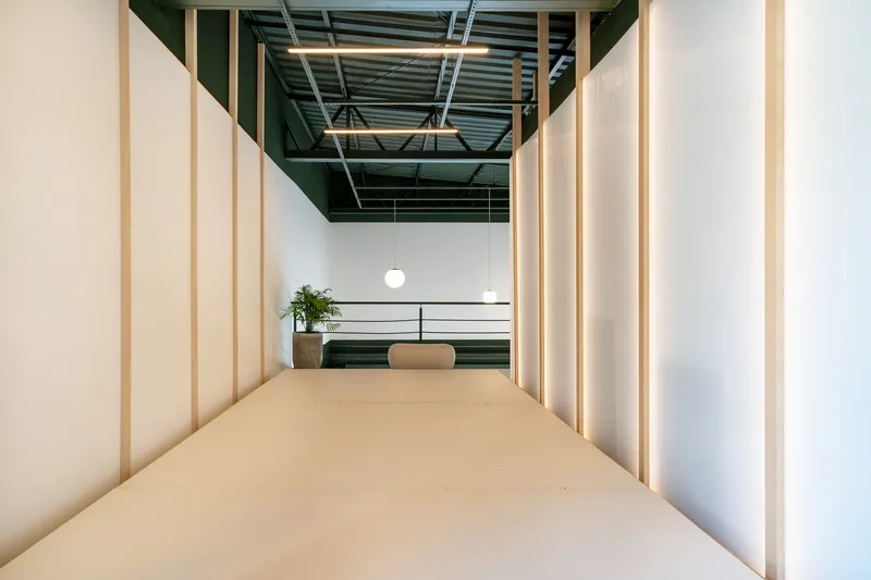 Axial view through timber-framed translucent corridor toward mezzanine with globe pendant lights