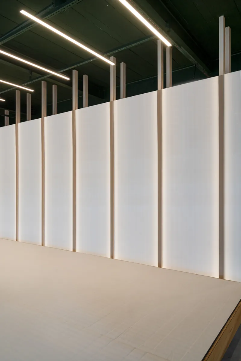 White paneled partition wall with vertical timber battens and linear ceiling lights above