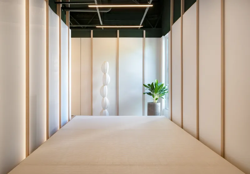 Corridor with vertical timber battens flanking the walls and a potted plant at the end