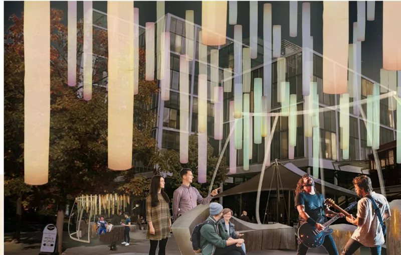 Vertical translucent light columns suspended above the plaza with people gathered beneath