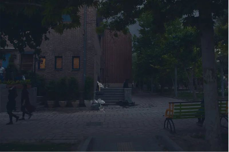 Brick building with corrugated metal extension and entrance steps visible through trees at dusk
