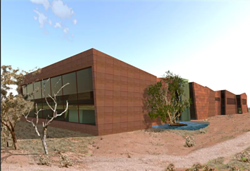 Exterior view of the rust-tiled volumes set into arid hillside with scattered native trees at dusk