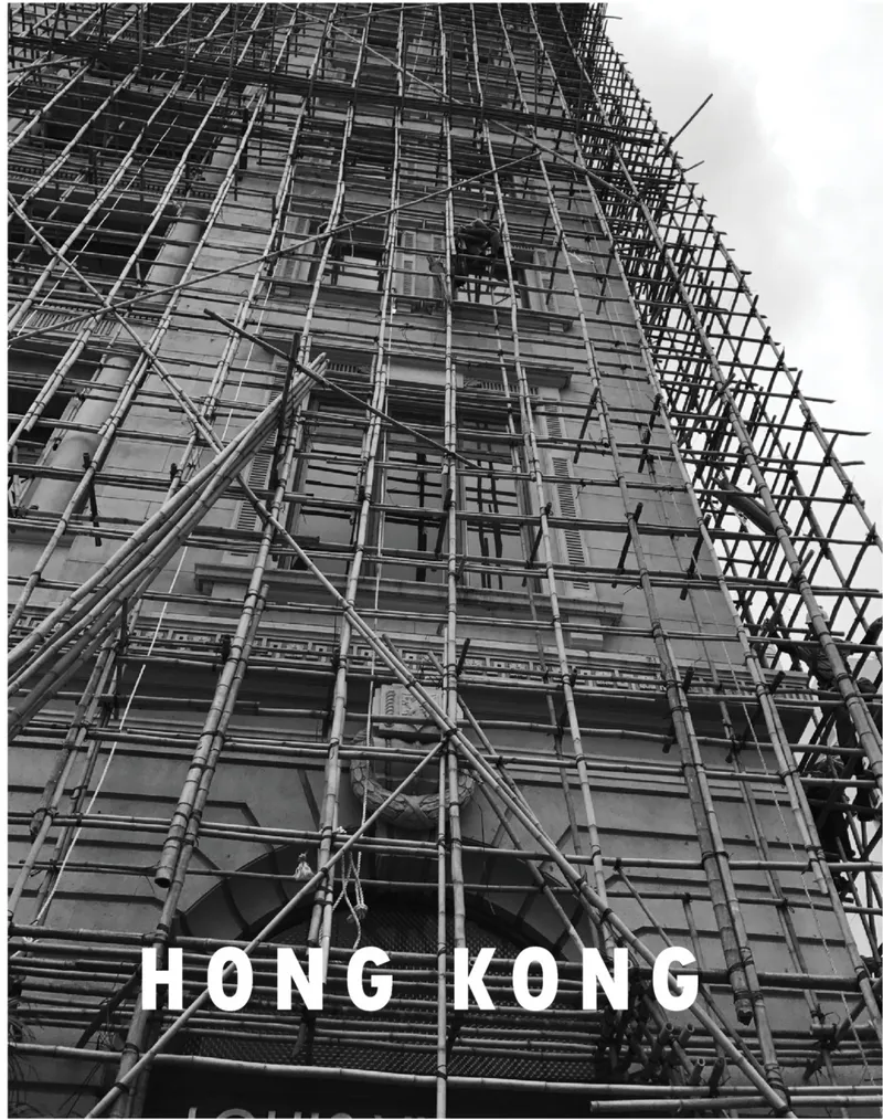 Upward view of bamboo scaffolding wrapping a facade with triangular bracing against the sky