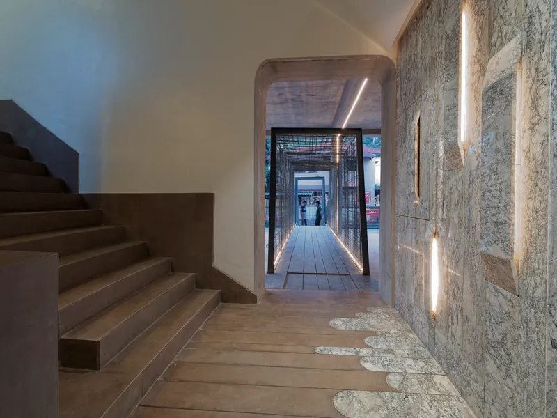 Interior staircase with textured stone wall featuring vertical light slots beside timber treads