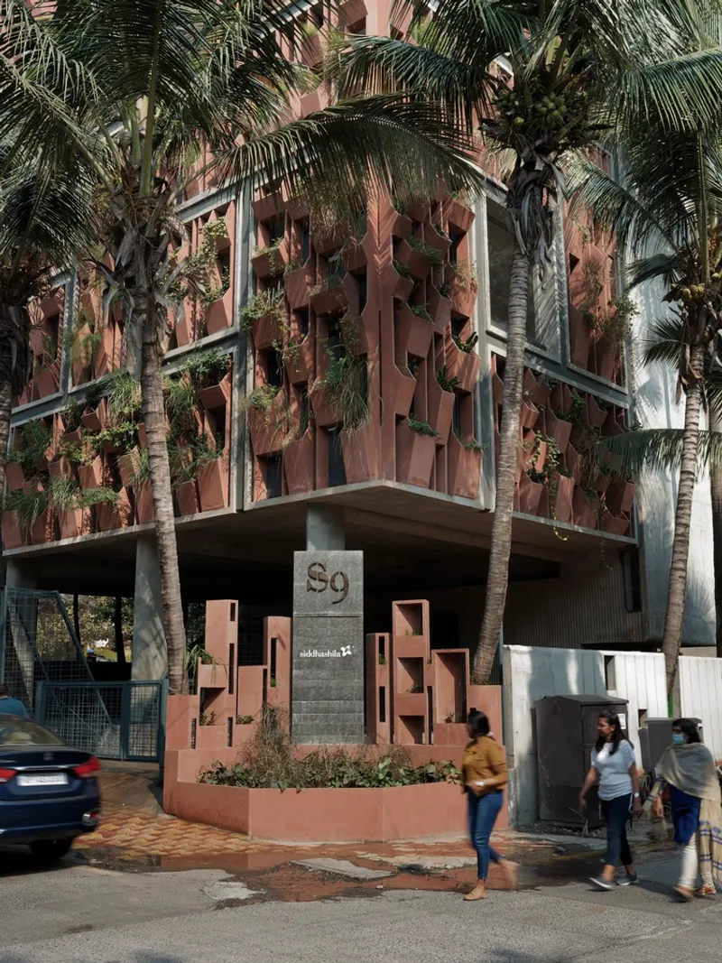 Street view of the corner entrance with concrete sign and pedestrians passing beneath palm trees
