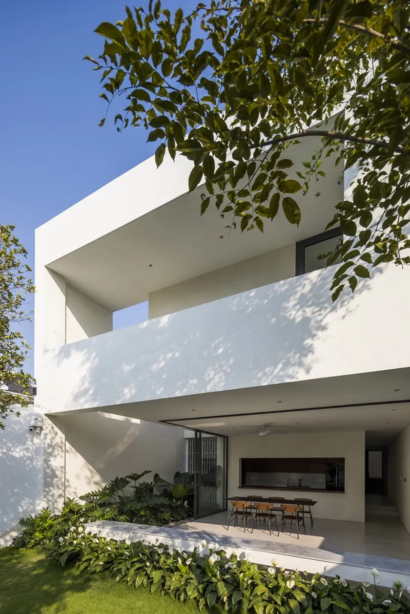 Stacked cantilever terraces framed by overhanging tree branches under afternoon sun