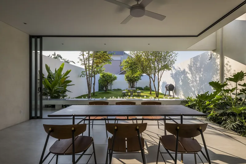 Dining room overlooking an enclosed garden courtyard with trees and dappled afternoon light