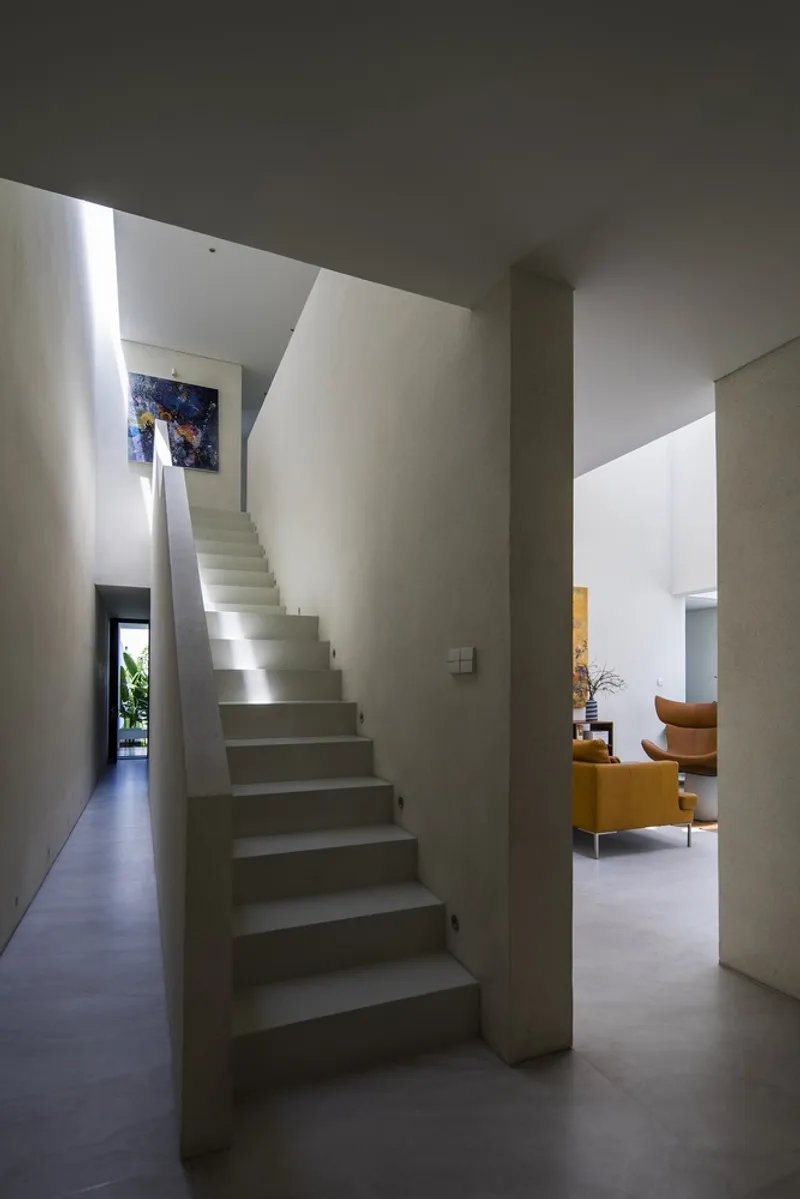 Concrete staircase winding upward between plastered walls with natural light from above