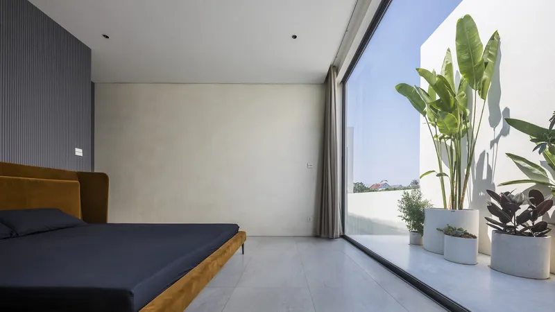 Bedroom with full-height glazing opening to a terrace planted with banana palms in pots