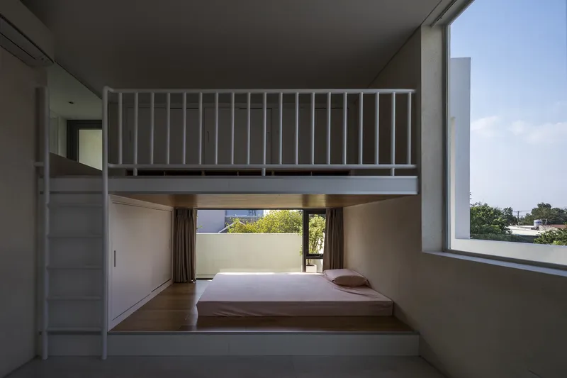 Split-level bedroom with timber sleeping platform and mezzanine accessed by white ladder