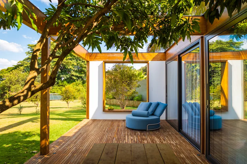 Timber deck terrace shaded by a mature tree canopy with sliding glass doors opening to the interior