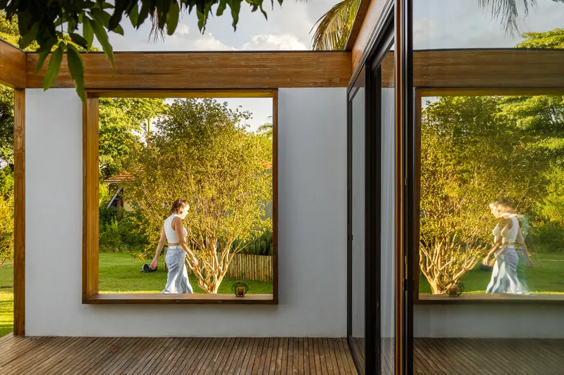 Timber framed window looking onto garden with figure walking past in afternoon light
